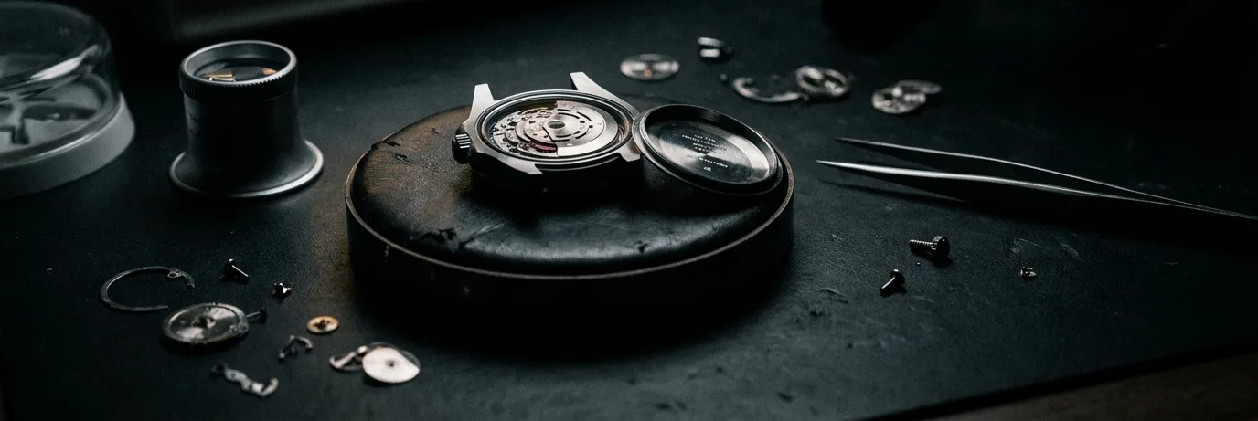 Watchmaker bench with an opened watch, loupe and timegrapher